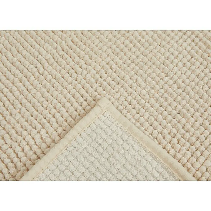 Badteppich Zottel - 50 x 80 cm, Creme, 100% Polyester - Cremefarbene, strukturierte Matte mit Noppenmuster, die eine gefaltete Ecke und die Rückseite zeigt.