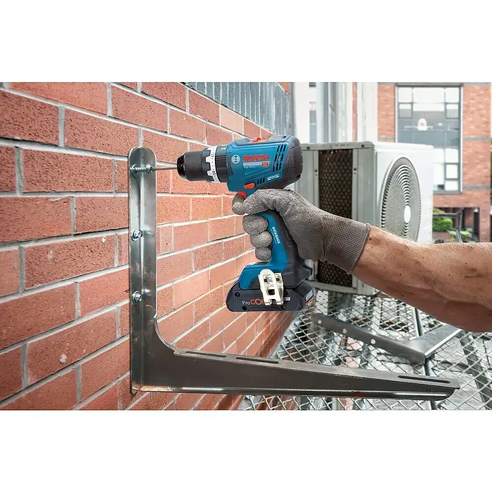 Bosch Professional AMPShare 18V Akku-Schlagbohrschrauber GSB 18V-65 - 18 V, 2 Akkus, 4 Ah, 63 Nm, 2 x 4 Ah Akku, L-BOXX 136 - Eine Person befestigt mit einem blauen und schwarzen Bosch Akku-Bohrschrauber eine Metallhalterung an einer Ziegelwand.