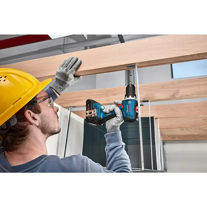 Bosch Professional AMPShare 18V Akku-Bohrschrauber GSR 18V-65 - 18 V, 2 Akkus, 4 Ah, 76 Nm, 2 x 4 Ah Akku, 1 x befüllter Werkzeug-Koffer - Person nutzt blauen Bosch Akku-Bohrschrauber, um Metallhalterung in Holzbalken zu schrauben, mit Schutzausrüstung.