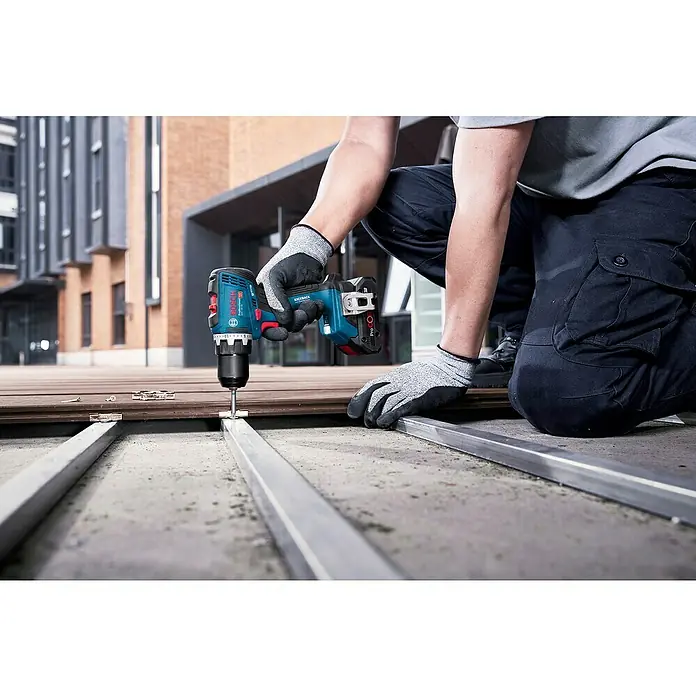 Bosch Professional AMPShare 18V Akku-Bohrschrauber GSR 18V-65 - 18 V, 2 Akkus, 4 Ah, 76 Nm, 2 x 4 Ah Akku, mit L-BOXX-Koffer - Eine Person verwendet einen blau-schwarzen Bosch Akku-Bohrschrauber, um eine Schraube in eine Terrassenbefestigung zu bohren, die Holz und Metall verbindet.