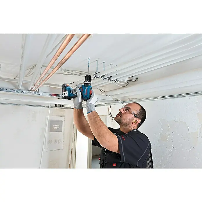 Bosch Professional AMPShare 18V Akku-Schlagbohrschrauber GSB 18V-65 - 18 V, 2 Akkus, 4 Ah, 63 Nm, 2 x 4 Ah Akku, L-BOXX 136 - Mann bohrt mit blau-schwarzem Bosch Akku-Bohrschrauber ein Loch in eine weiße Decke.