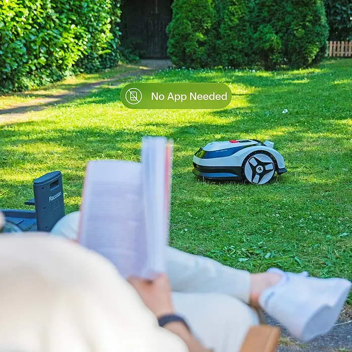 RoboUp Mähroboter Raccoon 2 SE - 600 m², Schnittbreite: 20 cm, Kamera-gestützte Navigation - Ein grau-schwarzer Mähroboter mit rotem Akzent und R-Speichenrädern mäht, während eine Person daneben liest.
