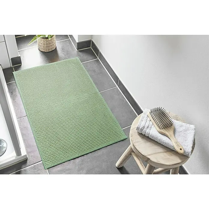 Badteppich Zottel - 50 x 80 cm, Salbei, 100% Polyester - Salbeigrüner Badteppich mit Noppenstruktur auf dunklem Fliesenboden im Badezimmer, neben einer Dusche.