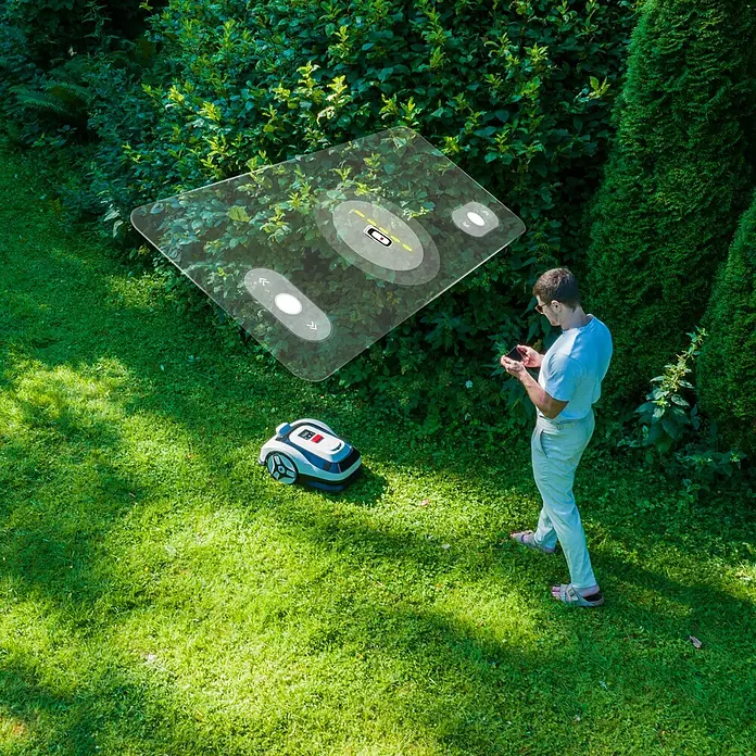 RoboUp Mähroboter Raccoon 2 SE - 600 m², Schnittbreite: 20 cm, Kamera-gestützte Navigation - Weiß-schwarzer Mähroboter, von einem Mann per Smartphone gesteuert, zeigt smartes Mähen.