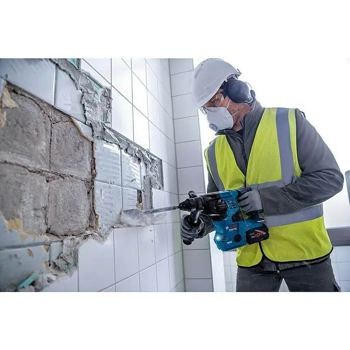 Bosch Professional AMPShare 18V Akku-Kombihammer Pro Heavy Duty GBH 18V-28 C - 18 V, Ohne Akku, 3,3 J, Mit L-BOXX - Ein Arbeiter entfernt mit einem blauen Bosch Akku-Abbruchhammer Fliesen von einer Wand bei Renovierungsarbeiten.