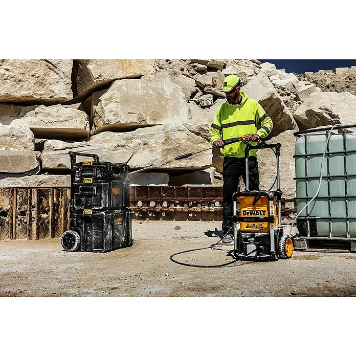 DeWalt XR 18V Akku-Hochdruckreiniger DCMPW1600N-XJ - 18 V, Ohne Akku - Mann reinigt schwarze DeWalt Werkzeugkästen mit gelb-schwarzem DeWalt Hochdruckreiniger in felsiger Außenumgebung.