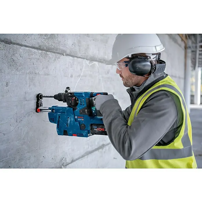 Bosch Professional AMPShare 18V Akku-Kombihammer Pro Heavy Duty GBH 18V-28 C - 18 V, Ohne Akku, 3,3 J, Mit L-BOXX - Eine Person in Schutzkleidung bohrt mit einem blauen Bosch Akku-Bohrhammer ein Loch in eine Betonwand.