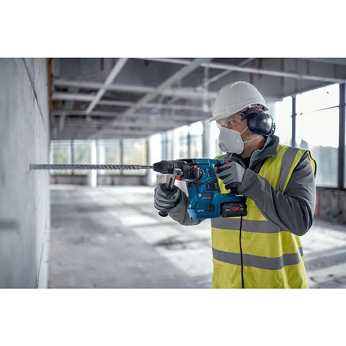 Bosch Professional AMPShare 18V Akku-Kombihammer Pro Heavy Duty GBH 18V-28 C - 18 V, Ohne Akku, 3,3 J, Mit L-BOXX - Mann in PSA bohrt mit blauem Bosch Bohrhammer und ProCORE 18V Akku in Betonwand.