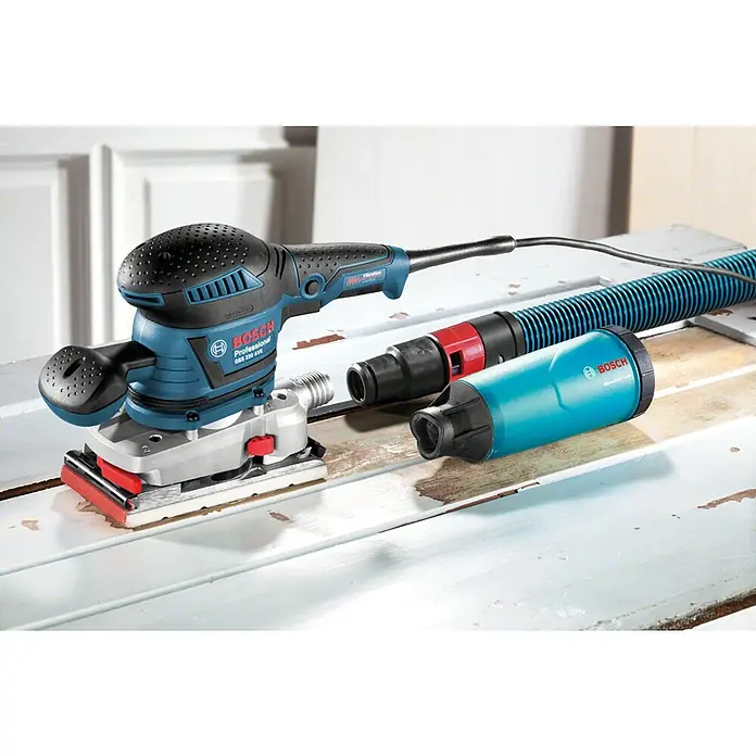 Bosch Professional Elektro-Schwingschleifer GSS 230 AVE - 300 W - Blauer und schwarzer Bosch Professional GSS 230 AVE Schwingschleifer auf Holzoberfläche mit Absaugschlauch und Staubbox.
