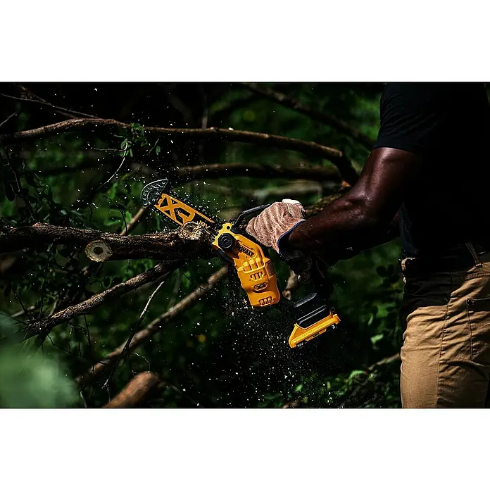 DeWalt XR 18V Akku-Kettensäge DCMPS520N-XJ - 18 V, Ohne Akku, Schwertlänge: 20 cm - Eine Person verwendet eine gelb-schwarze DeWalt Kettensäge, um einen Ast zu sägen, wobei Holzspäne fliegen.