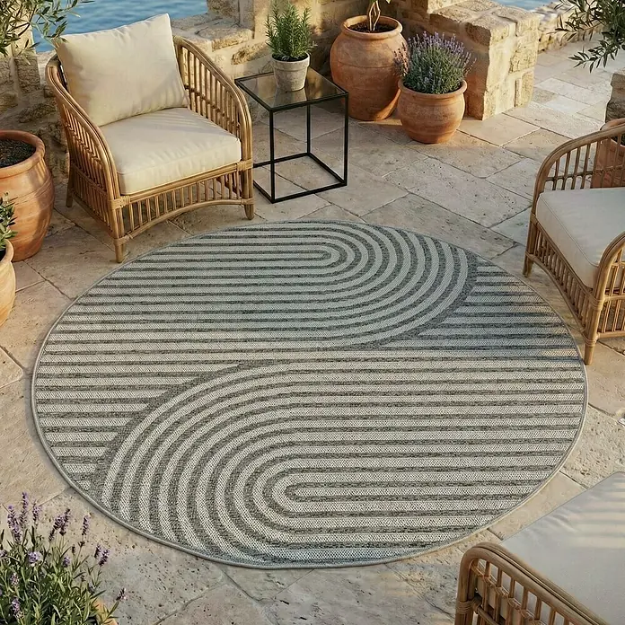 Outdoor-Teppich Desert 1301 - Grau, Durchmesser: 120 cm, 100 % Polypropylen - Runder grau-weiß gestreifter Outdoor-Teppich mit geometrischem Muster, auf einer Terrasse.