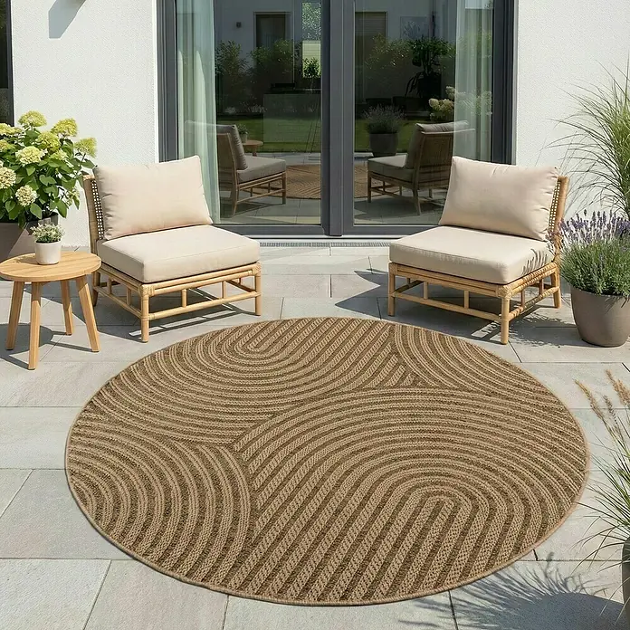 Outdoor-Teppich Timber 1401 - Beige, Durchmesser: 80 cm, 100 % Polypropylen - Rund geflochtener Juteteppich mit Wirbelmuster, auf einer Terrasse zwischen zwei Stühlen platziert.