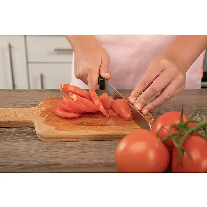 Piardino Tomate veredelt - Lycopersicon esculentum, 12 cm, Erntezeit: Juli - Hände schneiden rote Tomaten auf einem Holzschneidebrett mit einem silbernen Messer in einer Küche.