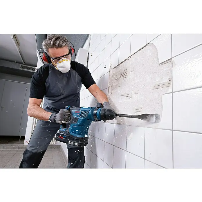 Bosch Professional AMPShare 18V Akku-Bohrhammer GBH 18V-34 CF - 18 V, 2 Akkus, 5,5 Ah, 5,8 J - Eine Person verwendet einen blauen Bosch Professional Akku-Bohrhammer mit Meißel, um weiße Fliesen von einer Wand zu entfernen.