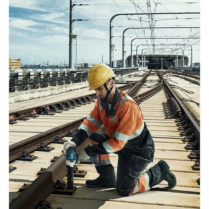 Bosch Professional AMPShare 18V Akku-Drehschlagschrauber - 18 V, 2 Akkus, 5,5 Ah, 1.000 Nm - Arbeiter verwendet einen blauen Bosch ProCORE 18V Schlagschrauber, um Schrauben an Bahnschienen festzuziehen.