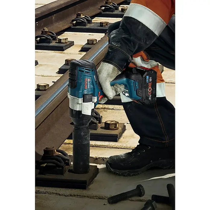 Bosch Professional AMPShare 18V Akku-Drehschlagschrauber - 18 V, 2 Akkus, 5,5 Ah, 1.000 Nm - Ein Arbeiter verwendet einen blauen und schwarzen Bosch Professional Akku-Schlagschrauber mit einem ProCORE 18V Akku an Eisenbahnschrauben.