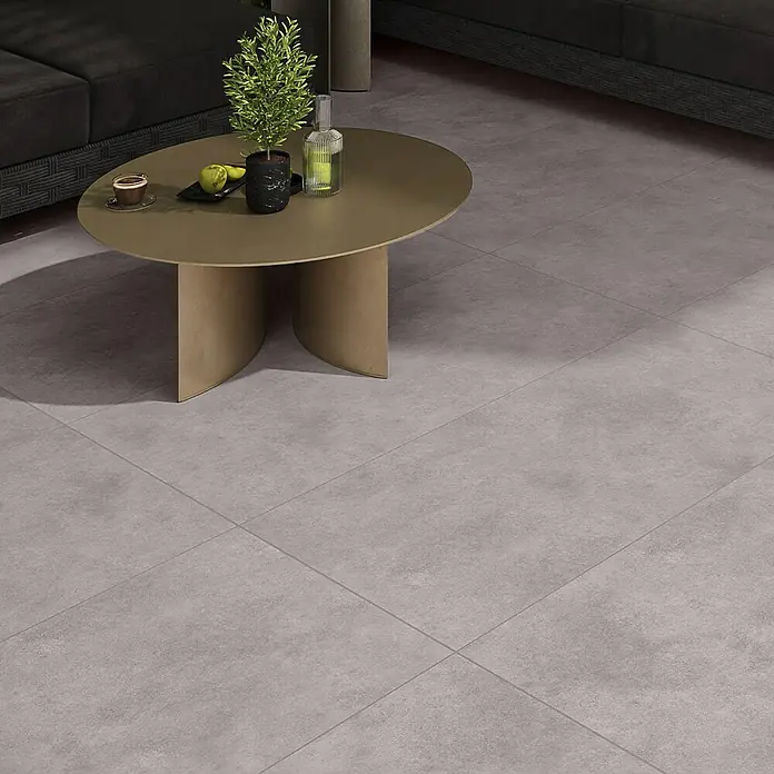 Cersanit Terrassenfliese Metropolis - 59,3 x 119,3 x 2 cm, Grey, Matt - Graue, strukturierte Bodenfliesen in Betonoptik in einem modernen Wohnzimmer unter einem Couchtisch verlegt.