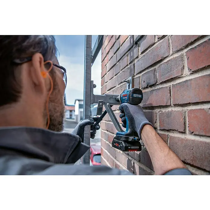 Bosch Professional AMPShare 18V Akku-Drehschlagschrauber GDS 18V-330 HC - 18 V, Ohne Akku, 330 Nm - Eine Person verwendet einen blau-schwarzen Bosch Akku-Schlagschrauber, um eine Metallhalterung in einer Ziegelwand zu befestigen.