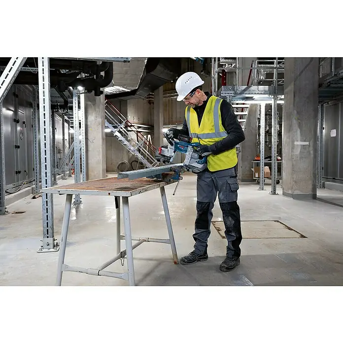 Bosch Professional AMPShare 18V Akku-Bandsäge GCB 18V-127 - 18 V, Ohne Akku - Mann bedient eine blaue Bosch Bandsäge und schneidet ein Metallprofil auf einer Werkbank.