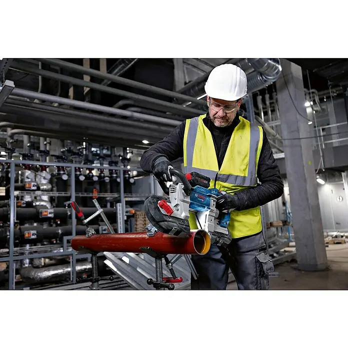 Bosch Professional AMPShare 18V Akku-Bandsäge GCB 18V-127 - 18 V, Ohne Akku - Mann in Schutzkleidung schneidet rotes Rohr mit blauer und silberner Bosch Akku-Bandsäge.