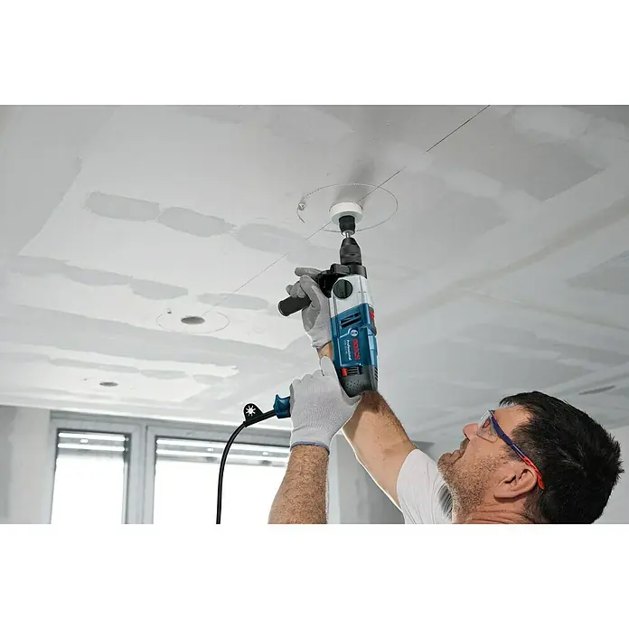 Bosch Professional Schlagbohrmaschine GSB 20-2 - 850 W, Schnellspannbohrfutter, Ohne Steinbohrer-Set - Ein Handwerker bohrt mit einer Bosch Professional Bohrmaschine ein Loch in eine Decke. Schutzbrille und Handschuhe sind getragen.