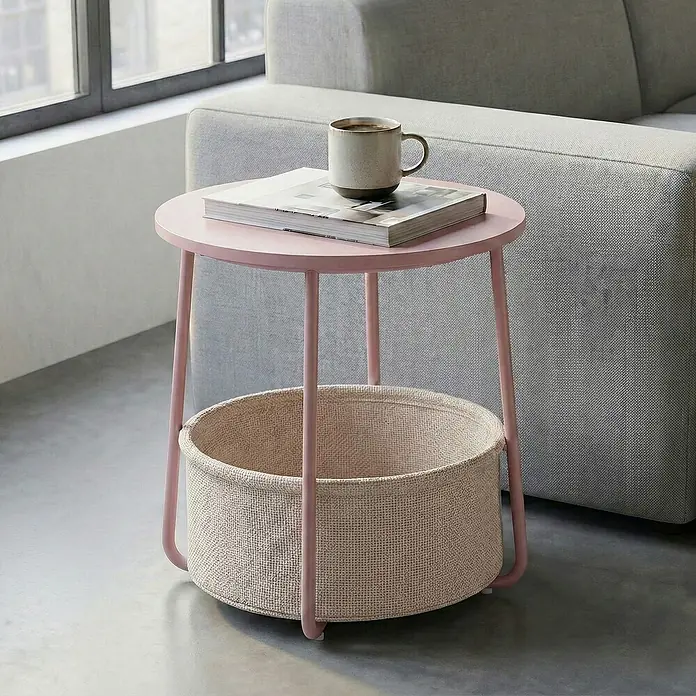 Beistelltisch - Ø x H: 45 x 51 cm, Pink - Rosafarbener Beistelltisch aus Metall mit runder Platte und integriertem beigen Stoffkorb neben einem grauen Sofa.