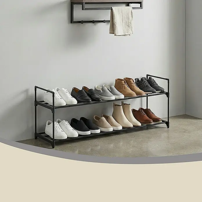 Schuhregal - L x B x H: 30 x 92 x 37 cm, Schwarz/Braun - Ein schwarzes, zweistöckiges Schuhregal, gefüllt mit verschiedenen Schuhen, steht auf einem Betonboden. Darüber hängt ein Wandregal mit Haken und einem hellen Handtuch.