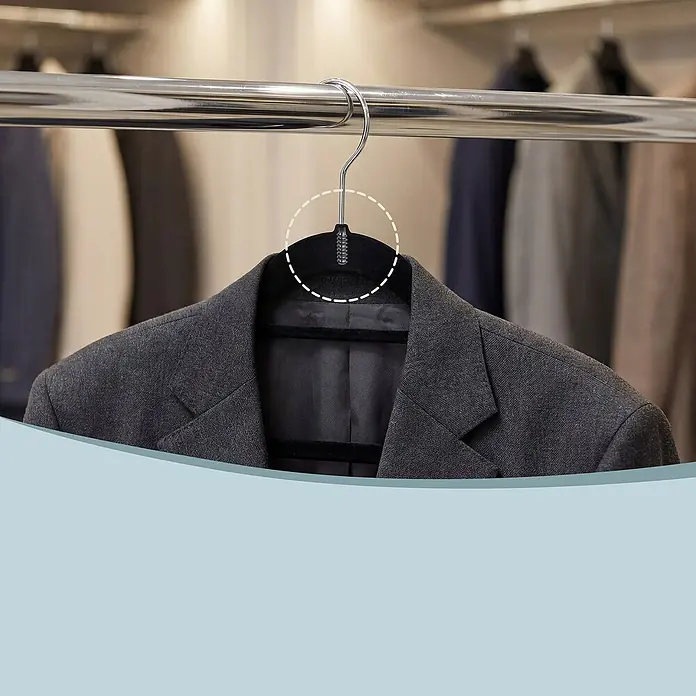 Kleiderbügel Samt - Schwarz, 50 Stk., Samtoberfläche - Dunkelgrauer Blazer auf schwarzem Samtkleiderbügel mit drehbarem Silberhaken an einer Stange im Schrank.