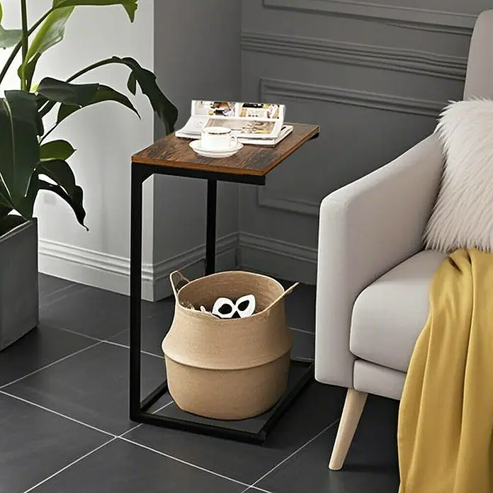 Beistelltisch - L x B x H: 35 x 55 x 55 cm, Schwarz/Braun - C-Beistelltisch aus dunklem Holz und schwarzem Metall neben einem Sessel, mit Korb auf der Basis.