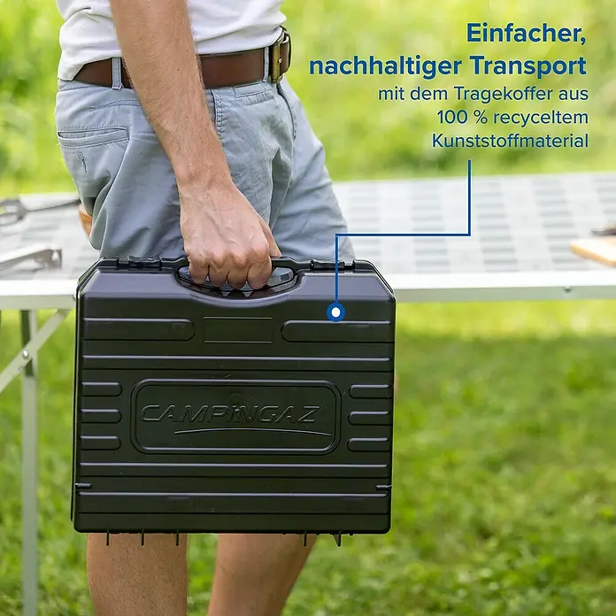 Campingaz Gaskocher Camp Bistro DLX - L x B x H: 285 x 370 x 125 mm, Leistung: 2.120 W, Ohne Stopgaz-System - Person hält schwarzen Campingaz Tragekoffer aus 100% recyceltem Kunststoff für nachhaltigen Transport.