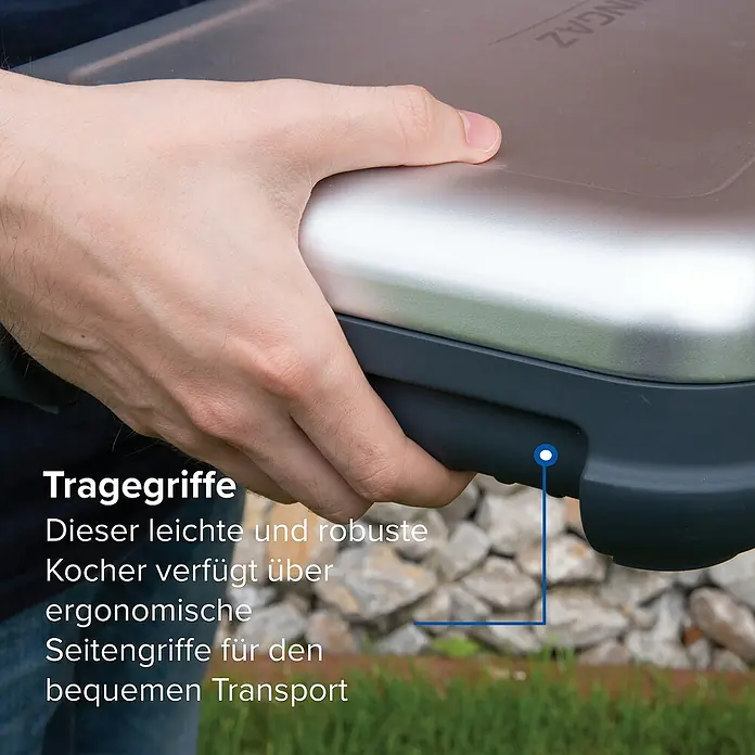 Campingaz Gaskochfeld Kitchen 2 - 2 Brenner, 2.000 W, L x B x H: 35 x 49 x 10 cm - Eine Hand hält einen tragbaren Kocher mit metallischer Oberseite und dunkelgrauen ergonomischen Seitengriffen zum Transport.