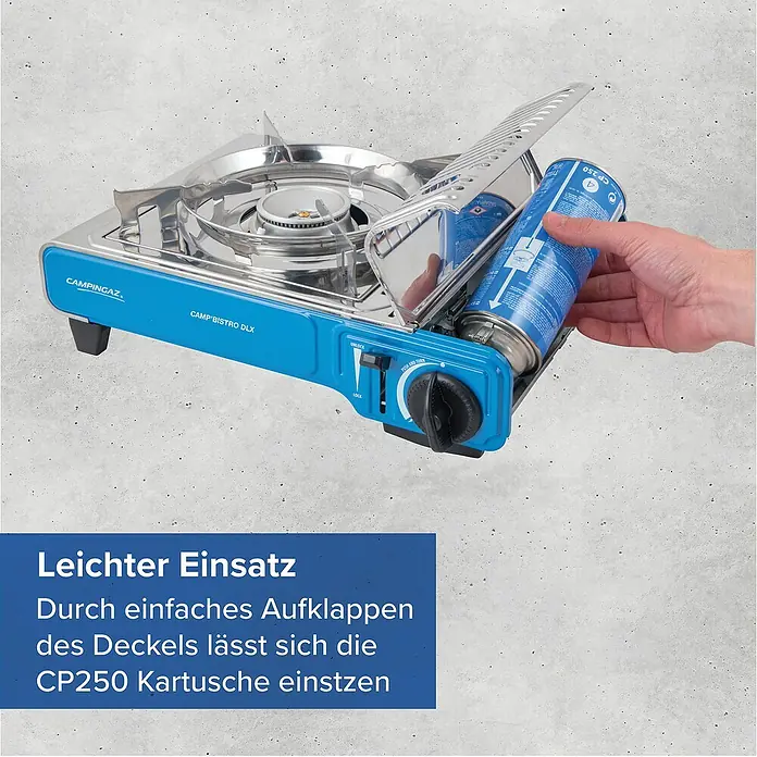 Campingaz Gaskocher Camp Bistro DLX - L x B x H: 285 x 370 x 125 mm, Leistung: 2.120 W, Ohne Stopgaz-System - Blauer und silberner Campingaz Gaskocher, in den eine Hand eine blaue Gaskartusche einsetzt, was die einfache Handhabung zeigt.