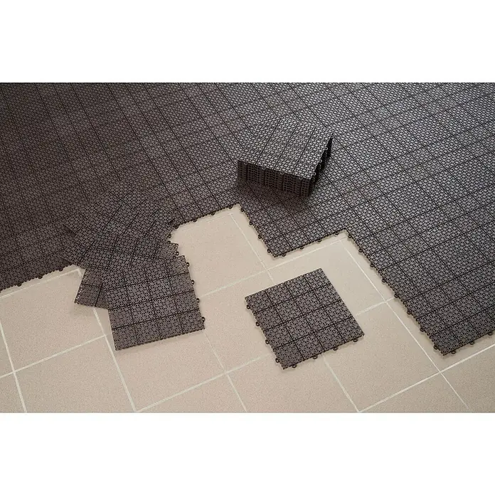 Loseta con sistema click - Polipropileno reciclado, 30 x 30 x 1,2 cm, Marrón, 1 ud. - Baldosas de suelo modulares entrelazadas de color marrón oscuro con patrón perforado, instaladas sobre un suelo claro, algunas apiladas.