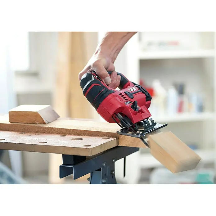 Skil Elektro-Pendelhubstichsäge 4530 AA - 0 /min - 3.000 /min, Max. Schnitttiefe in Holz: 75 mm, Anzahl Pendelhubstufen: 4 Stk. - Eine rote SKIL Stichsäge beim Schneiden eines Holzstücks, gehalten von einer Hand. Perfekt für präzise Holzarbeiten in der Werkstatt.
