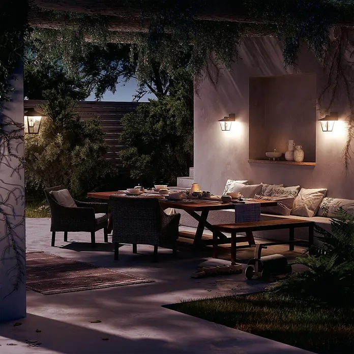 Philips Aplique exterior Kinno - 25 W, L x An x Al: 17 x 21 x 30 cm, Descendente - Patio exterior iluminado con mesa de comedor de madera, sillas de mimbre y banco integrado, ideal para reuniones acogedoras por la noche.