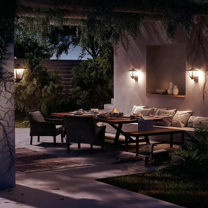 Philips Aplique exterior Kinno - 25 W, L x An x Al: 17 x 21 x 30 cm, Ascendente - Acogedor patio exterior de noche con mesa de madera, sillas de mimbre y banco empotrado, iluminado por cálidas luces de pared y velas.