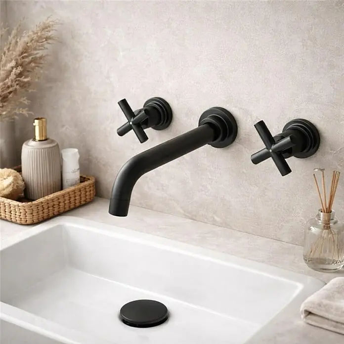 Rousseau Grifo de lavabo empotrado Mural - Negro, Mate - Grifo mural negro mate con manetas de cruz instalado sobre un lavabo rectangular blanco.