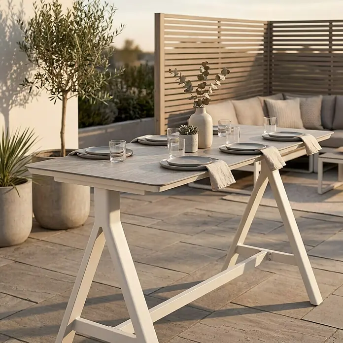 Garten-Stehtisch - L x B x H: 160 x 70 x 102 cm, Aluminium, Verbundwerkstoff, Rechteckig, Natural Warm Grey - Esstisch für den Außenbereich mit grauer Platte und weißen A-förmigen Beinen, auf einer Terrasse gedeckt.