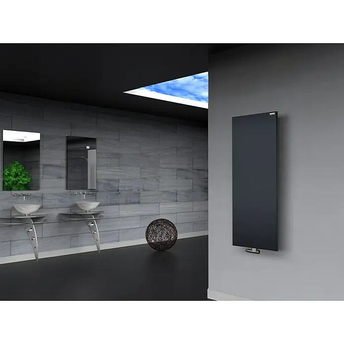 Szagato Designheizkörper Manhattan 2 - B x H: 470 x 1.200 mm, Wärmeleistung bei Vorlauftemperatur von 75 °C (D: 50): 799 W, Anthrazit, Ohne Handtuchhalter - Ein moderner Badezimmerheizkörper in dunkler Ausführung ist an einer grauen Wand montiert. Elegantes Design mit Blick auf Waschbecken und Spiegel.