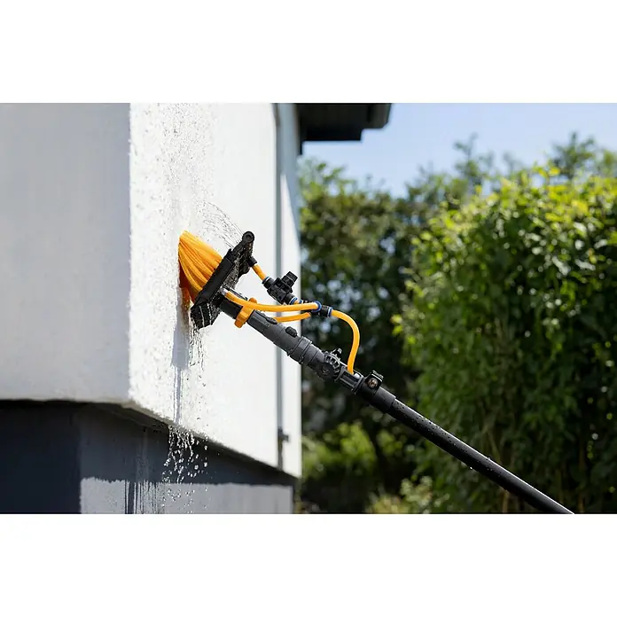 Neptun PV-  & Fassaden Reinigungsset mit verschiedenen Aufsätzen - Teleskopstiel, 120 cm - 490 cm - Wasserführende Reinigungsbürste mit gelben Borsten und schwarzem Stiel reinigt eine weiße Außenwand, Wasser spritzt heraus.