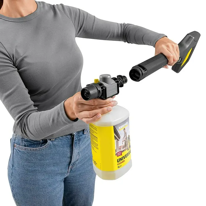 Kärcher Hochdruckreiniger K 7 Comfort Premium Home - 180 bar, 3.000 W, Fördermenge: 600 l/h, Inkl. Home-Kit - Person befestigt eine Kärcher Universalreiniger-Flasche (gelb/weiß) über ein schwarz/graues Zubehör an einer Hochdruckreiniger-Pistole.