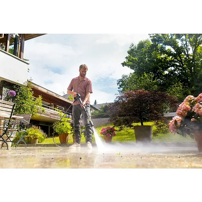 Kärcher Hochdruckpistole G 180 Q COMFORT!Hold - Passend für: Kärcher Hochdruckreiniger K2 bis K 7 - Ein Mann reinigt eine Terrasse mit einem Hochdruckreiniger, der einen kräftigen Wasserstrahl versprüht.