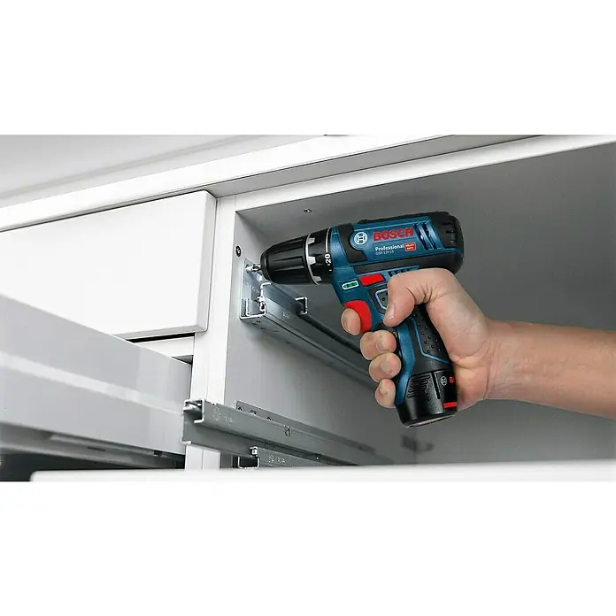 Bosch Professional Maschinen-Set 5-Tool-Kit GSR+GOP+GDR+GSA+GLI - 12 V, 3 Akkus, 2 Ah, 10 -tlg. - Blaue und schwarze Bosch Akkuschrauber setzt Schraube in Metallhalterung in weißem Schrank.