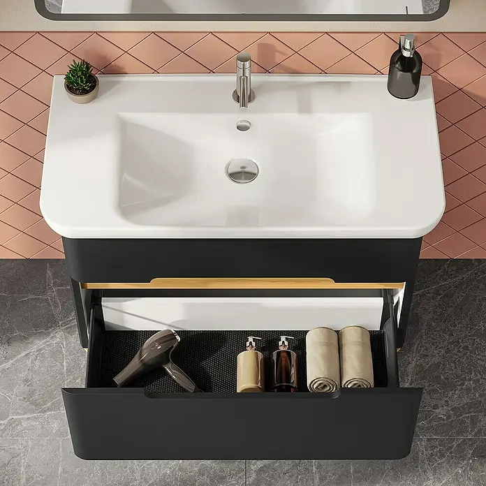 VitrA Sento Badmöbel-Set Sento - 98 cm, Anthrazit, 2 Schubladen - Schwarzer Badezimmer-Waschtisch mit weißem Waschbecken und offener Schublade, die Haartrockner, Seifenspender und Handtücher zeigt, vor rosa Fliesenwand.