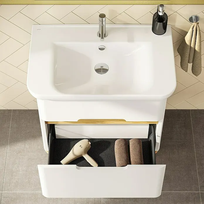 VitrA Sento Badmöbel-Set Sento - 98 cm, Weiß, 2 Schubladen - Blick von oben auf einen weißen Badezimmerschrank mit Armatur, Seifenspender und offenem Schubfach mit Föhn und Handtüchern. Ein Handtuch hängt daneben.