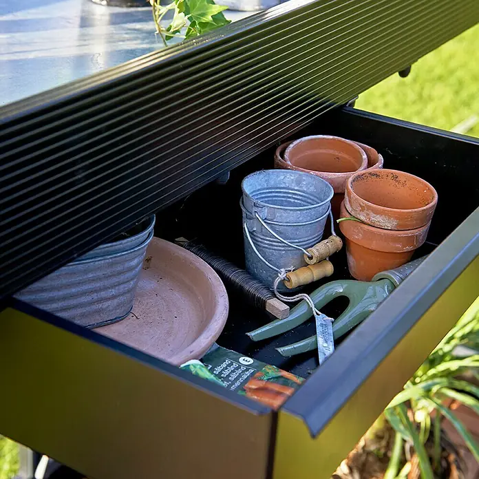 Juliana Gewächshaus-Tisch - 52 x 141 x 10 cm - Nahaufnahme einer Schublade mit Gartenzubehör wie Töpfen, Eimern und einer Harke, die sich perfekt für jeden Gartenliebhaber eignet.