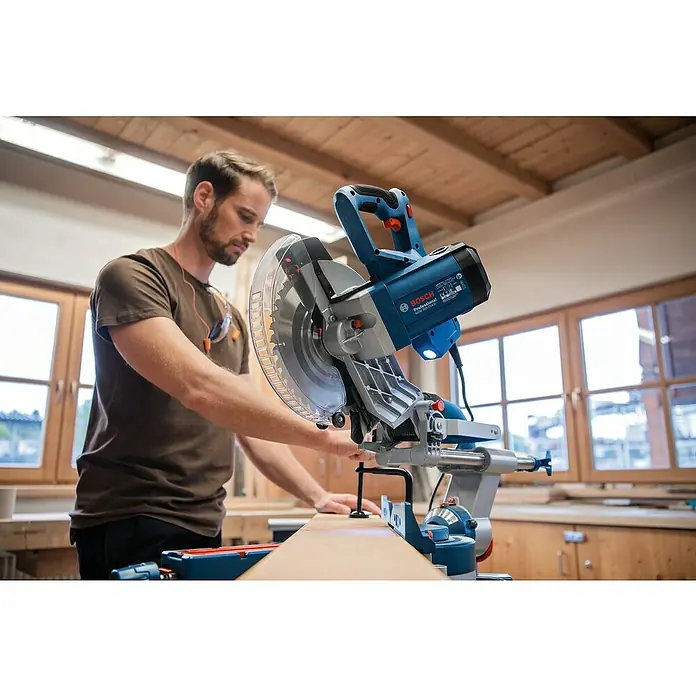 Bosch Professional Kapp- & Gehrungssäge GCM 305-254 D - 1.500 W, Durchmesser Sägeblatt: 254 mm, Leerlaufdrehzahl: 4.500 U/min - Blauer Bosch Professional Kapp- und Gehrungssäge wird von einem Mann zum Holzschneiden verwendet.