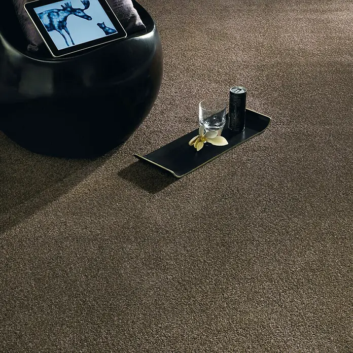 Teppichboden Meterware Linda - Breite: 400 cm, Velours, 100 % Polypropylen, Schlamm - Nahaufnahme eines getufteten Teppichs in Braun, mit einem Getränke-Tablett, das ein Glas Wasser und eine Dose trägt.