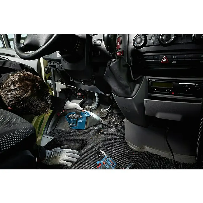 Bosch Professional Akku-Staubsauger - 12 V, 2 Akkus, Behältervolumen: 0,35 l - Arbeiter reinigt Auto-Innenraum mit blau-schwarzem Bosch Akkusauger. Ein Bosch Akkuschrauber ist in der Nähe.