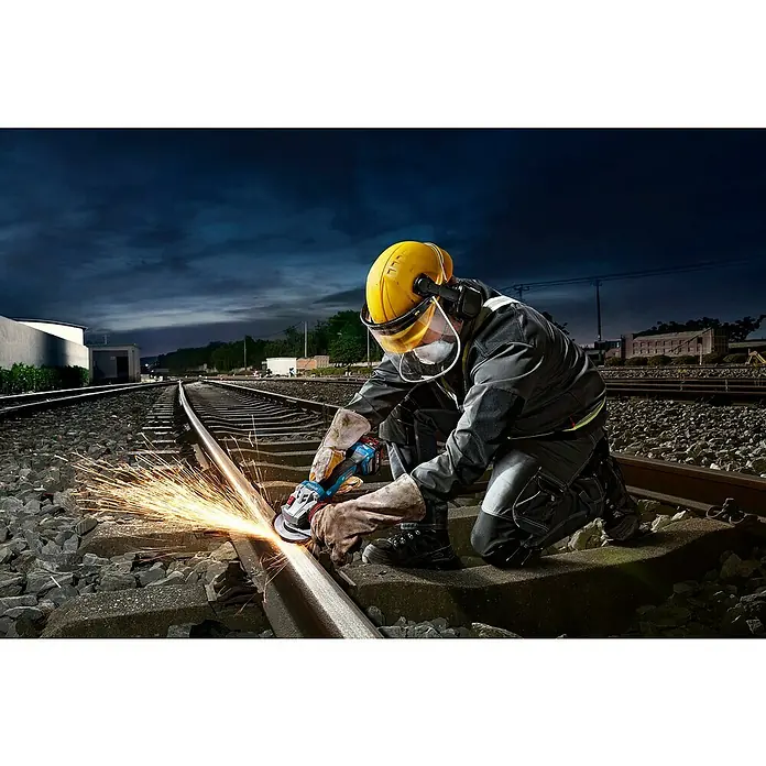 Bosch Professional AMPShare 18V Akku-Winkelschleifer GWS 18V-11 PRO SOLO - Ohne Akku, Durchmesser Scheibe: 125 mm - Ein Arbeiter in Schutzkleidung nutzt einen blau-schwarzen Winkelschleifer, um eine Metallschiene auf Gleisen zu schneiden, Funken erzeugend.